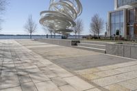 a sculpture is set beside the water's edge at a lakefront area with benches on either side