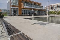 wooden benches sit near a water front and patio area next to the building and patio