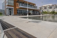 wooden benches sit near a water front and patio area next to the building and patio