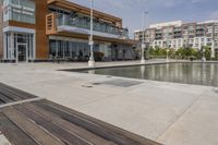 wooden benches sit near a water front and patio area next to the building and patio