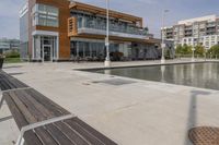 wooden benches sit near a water front and patio area next to the building and patio