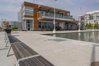 wooden benches sit near a water front and patio area next to the building and patio