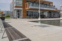 wooden benches sit near a water front and patio area next to the building and patio