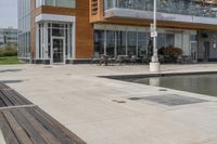 wooden benches sit near a water front and patio area next to the building and patio