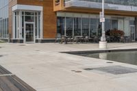 wooden benches sit near a water front and patio area next to the building and patio