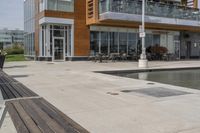 wooden benches sit near a water front and patio area next to the building and patio