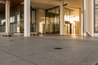 a paved sidewalk with concrete steps leading into a large building with glass doors and doors on either side