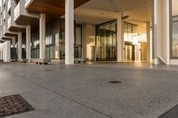 a paved sidewalk with concrete steps leading into a large building with glass doors and doors on either side