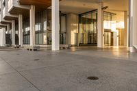 a paved sidewalk with concrete steps leading into a large building with glass doors and doors on either side