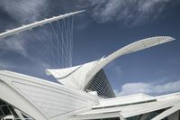 a tall white building that has a very long curved roof with many triangular elements on top