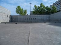 the empty parking lot in front of a wall with apartment buildings on it and a skateboarder on a ramp