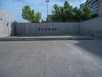 the empty parking lot in front of a wall with apartment buildings on it and a skateboarder on a ramp