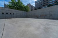 the empty parking lot in front of a wall with apartment buildings on it and a skateboarder on a ramp