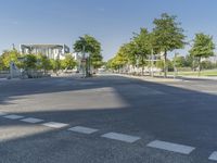 empty street in a city with many tall buildings and green trees surrounding it a road sign with a crosswalk, a sign that says don't stop is empty, street signs are on a street is next to them