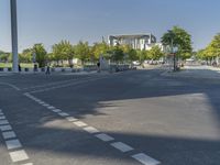 empty street in a city with many tall buildings and green trees surrounding it a road sign with a crosswalk, a sign that says don't stop is empty, street signs are on a street is next to them