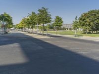 empty street in a city with many tall buildings and green trees surrounding it a road sign with a crosswalk, a sign that says don't stop is empty, street signs are on a street is next to them