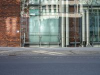 a grey car sitting next to a building with glass walls and doors and a tree