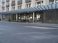 a tall stone building with a canopy over it in an urban city area with parking lot