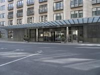 a tall stone building with a canopy over it in an urban city area with parking lot