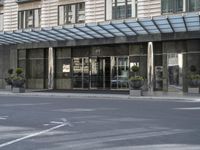 a tall stone building with a canopy over it in an urban city area with parking lot