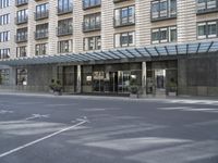 a tall stone building with a canopy over it in an urban city area with parking lot