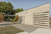 concrete architecture with glass panels along one side and grass, trees on the other side