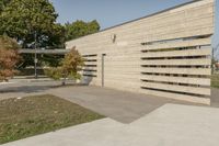 concrete architecture with glass panels along one side and grass, trees on the other side