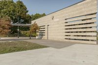 concrete architecture with glass panels along one side and grass, trees on the other side