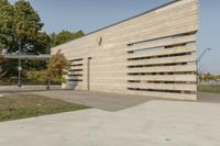 concrete architecture with glass panels along one side and grass, trees on the other side