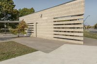 concrete architecture with glass panels along one side and grass, trees on the other side