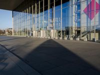 a very tall building with a huge glass facade next to it with a man on his cellphone