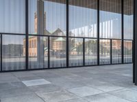 a empty white tiled sidewalk and wall with glass doors on the side of the building