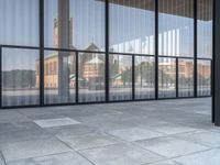 a empty white tiled sidewalk and wall with glass doors on the side of the building