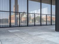 a empty white tiled sidewalk and wall with glass doors on the side of the building