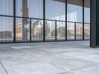 a empty white tiled sidewalk and wall with glass doors on the side of the building