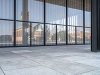 a empty white tiled sidewalk and wall with glass doors on the side of the building