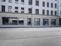 there is a empty street in front of buildings with signs and banners written on the side