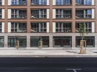 tall building on the side of an empty street with trees and planters in front of it