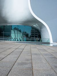 a black umbrella stands in front of the water - filled pool of a building with windows