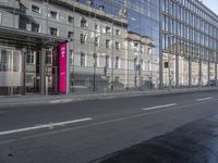 a large building is reflected in the side of the street that goes along this narrow road