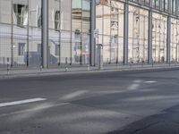 a large building is reflected in the side of the street that goes along this narrow road