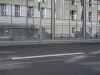 a large building is reflected in the side of the street that goes along this narrow road