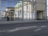 a large building is reflected in the side of the street that goes along this narrow road