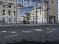 a large building is reflected in the side of the street that goes along this narrow road