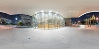 a fish eye lens shows the inside of an auditorium building with circular glass walls and an elevated walkway