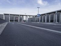 a empty street between two tall buildings that are on one side and blue sky in the background