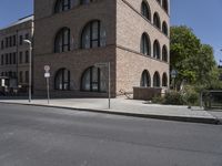 a street corner that is in front of a brick building with large round windows and a circular building top