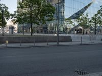 a large glass building with trees in front of it and people walking down the sidewalk