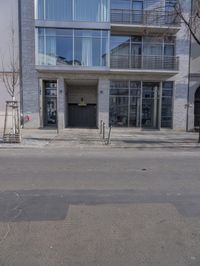 there is a building that has many windows and trees by it, it seems that there are only two cars on the street