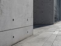 a concrete building with some windows next to some brick paving and stone ground with a bench in front